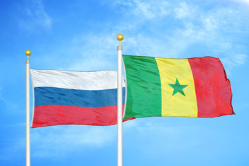 Russia and Senegal two flags on flagpoles and blue cloudy sky