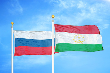 Russia and Tajikistan two flags on flagpoles and blue cloudy sky