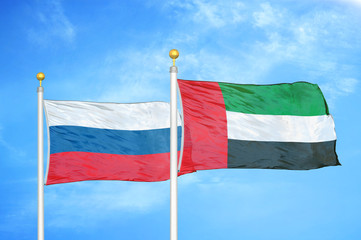 Russia and United Arab Emirates two flags on flagpoles and blue cloudy sky