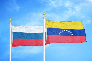 Russia and Venezuela two flags on flagpoles and blue cloudy sky