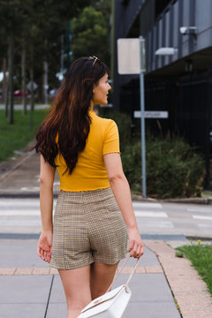 behind view of fashionable asian woman walking
