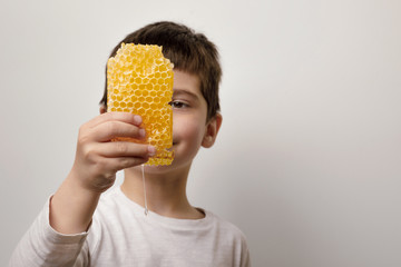 The baby holds honeycombs. boy with honey on a white background