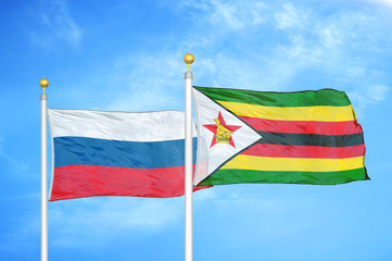 Russia and Zimbabwe two flags on flagpoles and blue cloudy sky