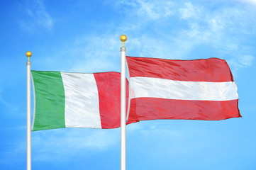 Italy and Austria  two flags on flagpoles and blue cloudy sky