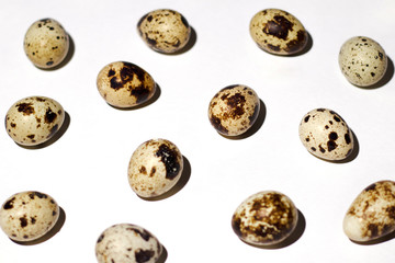 Fototapeta na wymiar Quail eggs are scattered on a perfectly white background. The photo was taken close-up for any conceptual design and for Easter design, too.