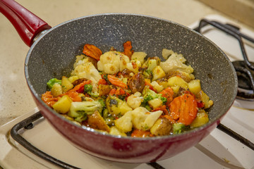 Vegetables are fried in a pan with seed oil on a gas stove