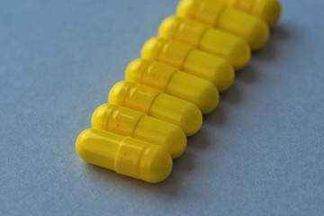 Yellow capsules on a blue background. Concept of medicine