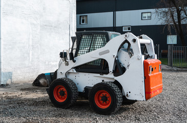 White skid steer loader at a construction site waiting of work. Industrial machinery. Industry.