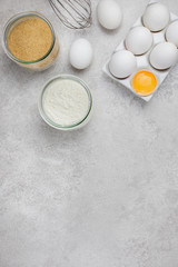 Obraz na płótnie Canvas Baking culinary ingredients. Eggs, flour, whisk and kitchen textile on bright grey concrete background. Cookies, pie or cake recipe mockup. Top view. Flat Lay. Copy space.