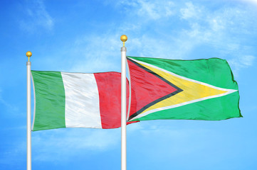 Italy and Guyana two flags on flagpoles and blue cloudy sky