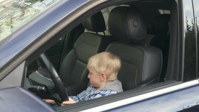 boy sits at the wheel of a car and imagines how he drives it