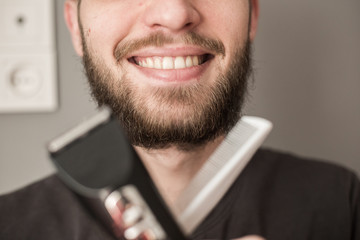 Man shaves his beard with an electric trimmer
