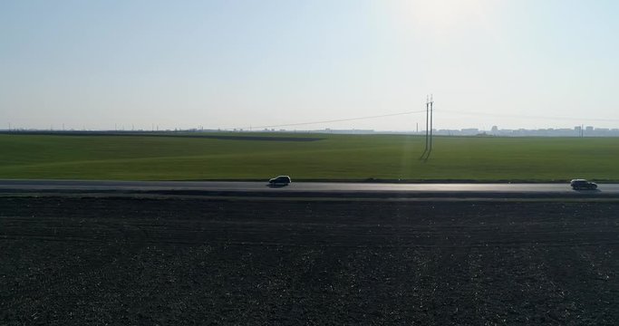 The highway between the black earth and the green field movement of cars