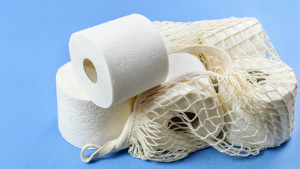 Group of toilet rolls in the white handbag on the blue background closeup. Personal hygiene product, health care.
