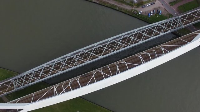 Abstract and cinematic aerial drone view of an industrial metal bridge with train tracks 4K
