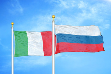 Italy and Russia two flags on flagpoles and blue cloudy sky