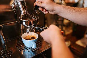 Fototapeta na wymiar A man in a cafe makes espresso coffee. Coffee machine and cup