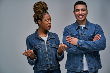 Surprised woman looks disappointedly at strong pleased man with crossed over his arms.  Emotions...