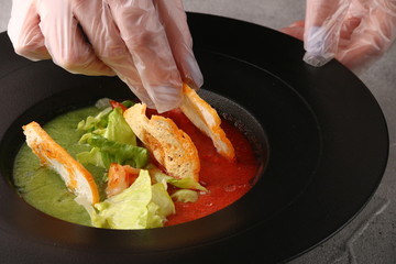 tomatoes soup with hands. chef decorating plate. kitchen processing