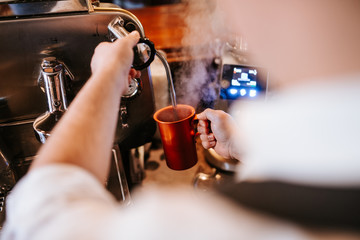A man in a cafe makes espresso coffee. Coffee machine and cup