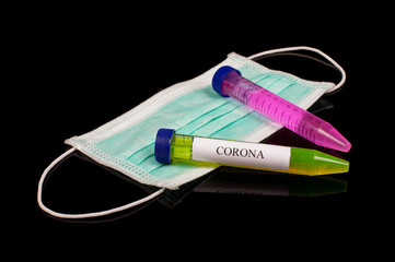 Yellow glowing liquids in the test tube with text CORONA and face mask isolated on the black...