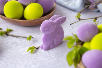 easter green and purple eggs with rabbit on a light surface