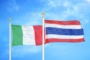 Italy and Thailand two flags on flagpoles and blue cloudy sky