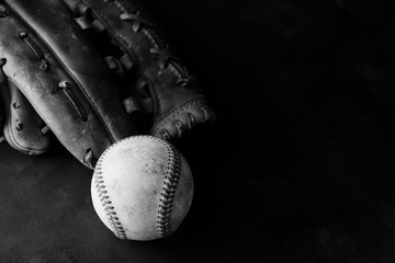 Baseball ball for sport with leather game glove in black and white, copy space on dark moody...