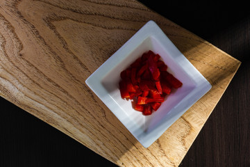 chopped bell pepper on a white saucer and a table with natural textures
