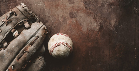 Old grunge baseball glove and ball on vintage texture background, copy space for sports banner.