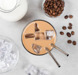 Iced coffee milk in a glass on a light gray background top view