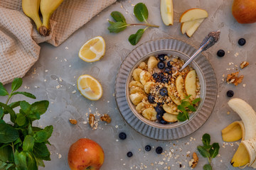 Oatmeal with blueberries, bananas, apples and chopped nuts in a beige ceramic cup
