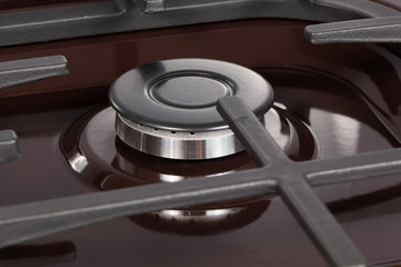 The hob burner on a brown gas stove, close-up without flame, top view