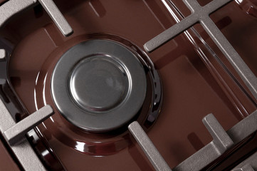 The hob burner on a brown gas stove, close-up without flame, top view