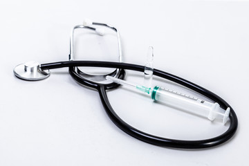 Phonendoscope and syringe on a white background.
