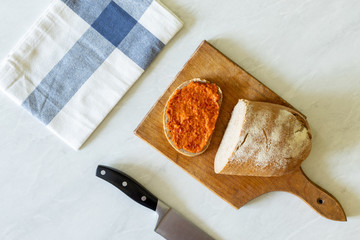 Flat lay above ajvar on the bread served on the wooden board