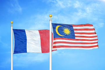 France and Malaysia two flags on flagpoles and blue cloudy sky