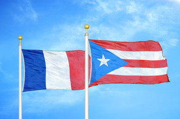 France and Puerto Rico two flags on flagpoles and blue cloudy sky