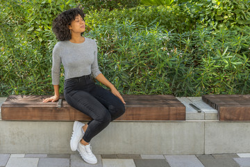 She sits outside on a park bench, enjoying the fresh spring air. With a relaxed posture, she closes...