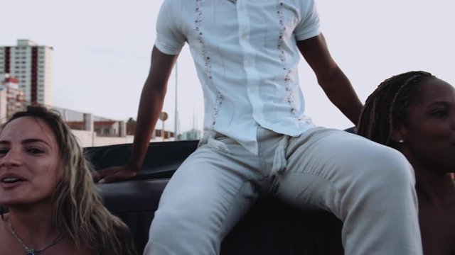 Young man and women sitting in convertible and having fun