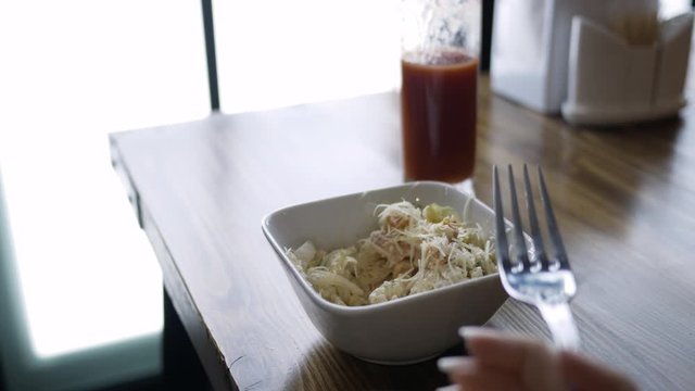 Closeup of salad and a glass of tomato juice in a cafe. Girl eating lunch in a cafe