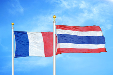 France and Thailand two flags on flagpoles and blue cloudy sky