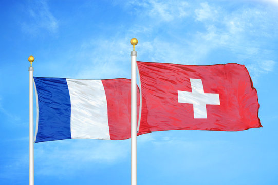 France and Switzerland two flags on flagpoles and blue cloudy sky