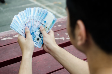 Guy holding a 1000 philippine peso cash and looking at it