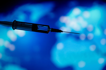 Medical syringe for a vaccine. Blue background.