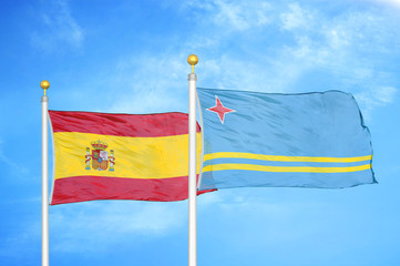 Spain and Aruba two flags on flagpoles and blue cloudy sky