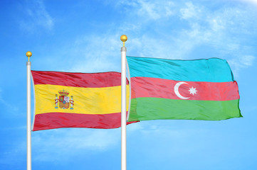 Spain and Azerbaijan  two flags on flagpoles and blue cloudy sky