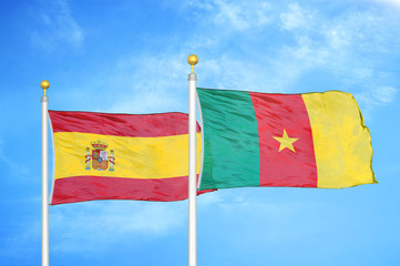 Spain and Cameroon  two flags on flagpoles and blue cloudy sky