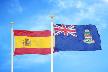 Spain and Cayman Islands two flags on flagpoles and blue cloudy sky