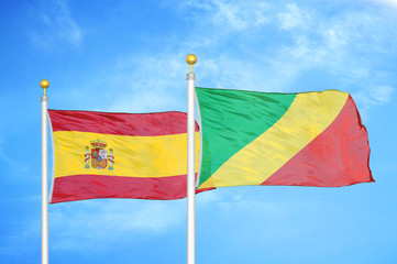 Spain and Congo  two flags on flagpoles and blue cloudy sky